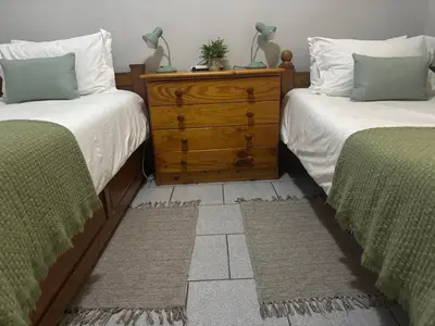 a bedroom with two twin beds and a dresser between them at Lente Beach Cottage, Fleur Park, Gordon's Bay in Gordonʼs Bay