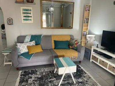 a living room with a couch and a television at Lente Beach Cottage, Fleur Park, Gordon's Bay in Gordonʼs Bay