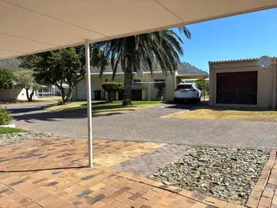 a white car parked under an umbrella in a driveway at Lente Beach Cottage, Fleur Park, Gordon's Bay in Gordonʼs Bay