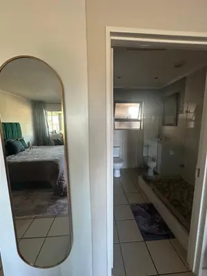 a mirror in a room with a bed and a bathroom at Sleek Modern Luxury Pool Side Apartment in Cape Town