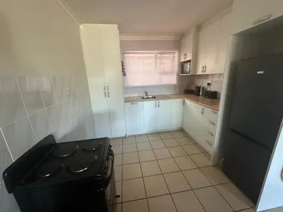 a kitchen with white cabinets and a black refrigerator at Sleek Modern Luxury Pool Side Apartment in Cape Town