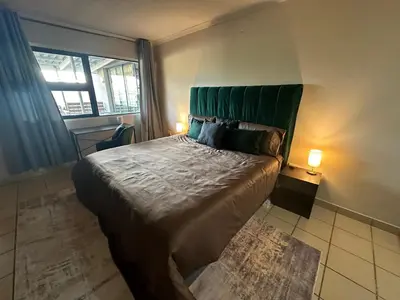 a bedroom with a large bed with a green headboard at Sleek Modern Luxury Pool Side Apartment in Cape Town
