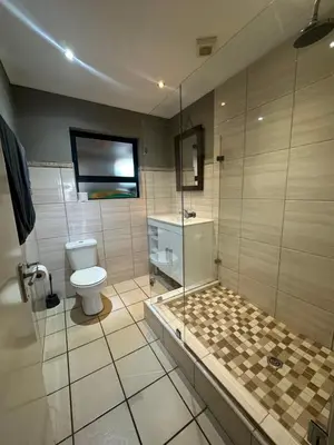 a bathroom with a shower and a toilet and a glass shower at Sleek Modern Luxury Pool Side Apartment in Cape Town