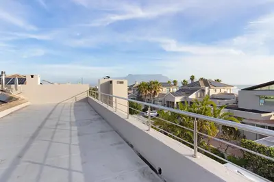 a balcony with a view of the ocean and houses at Sunset Serenity Villa in Cape Town