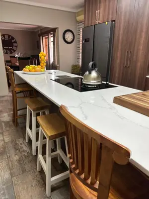 a kitchen with a large white counter and wooden cabinets at The Villa at Marnas Private Self-Catering Accommodation in Cape Town