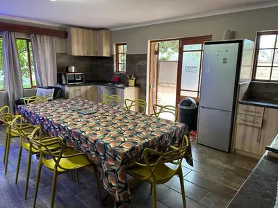 a kitchen with a table with yellow chairs and a kitchen with a refrigerator at Marnas Private Self Catering Accommodation The Cottage in Cape Town