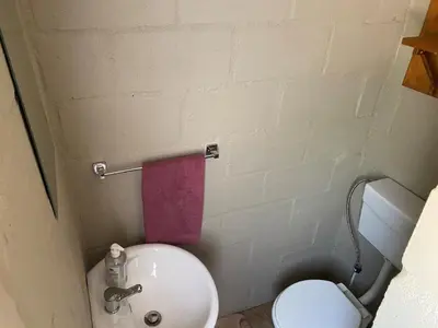 a small bathroom with a toilet and a pink towel at The Jack at Marnas Self Catering Accommodation in Cape Town