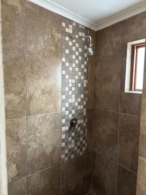 a bathroom with a shower with a tiled wall at The Jack at Marnas Self Catering Accommodation in Cape Town