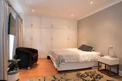 a bedroom with a bed and a chair at Beautiful garden flat in Cape Town