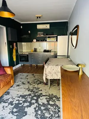 a living room with a table and a kitchen at Beautiful garden flat in Cape Town