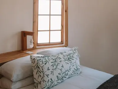 a bedroom with a pillow on a bed with a window at Dassenheuwel Farm Stay Cottages in Malmesbury