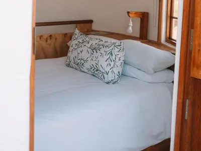 a bed with a pillow on top of it at Dassenheuwel Farm Stay Cottages in Malmesbury