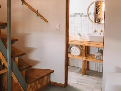 a bathroom with a sink and a staircase with a mirror at Dassenheuwel Farm Stay Cottages in Malmesbury