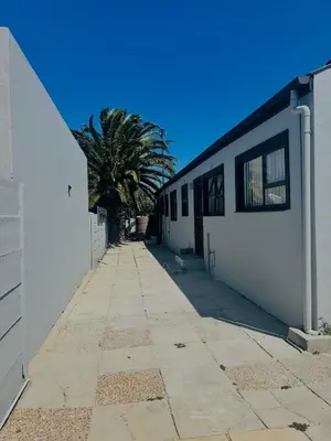 a sidewalk next to a white building with a palm tree at Private garden guest house in Cape Town