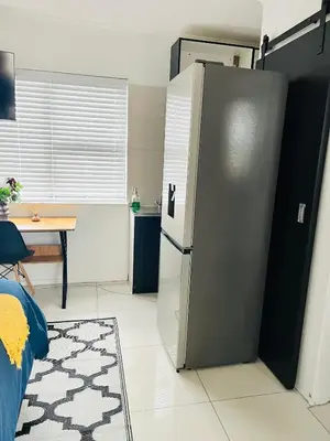 a kitchen with a refrigerator in the middle of a room at Private garden guest house in Cape Town