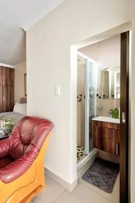 a bedroom with a couch and a bathroom with a sink at Goodwood Oasis FreeWiFi-Parking 1 in Cape Town