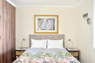 a bedroom with a bed and two night stands with two lamps at Goodwood Oasis FreeWiFi-Parking 1 in Cape Town
