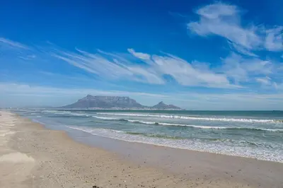 a beach with a mountain in the background and the ocean at Bayhill Terrace 17 by CTHA in Cape Town