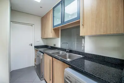a kitchen with wooden cabinets and a sink at Bayhill Terrace 17 by CTHA in Cape Town