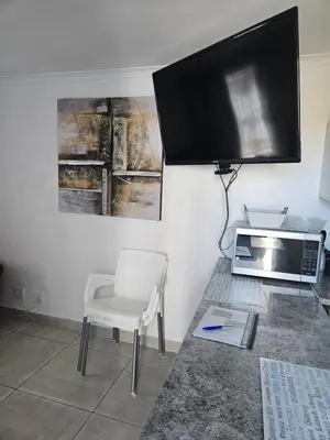 a living room with a tv and a chair and a microwave at The Somerset nest in Cape Town