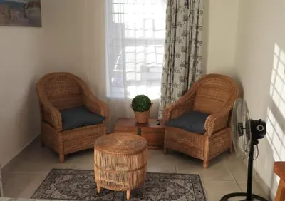 two wicker chairs and a table in a living room at The Somerset nest in Cape Town