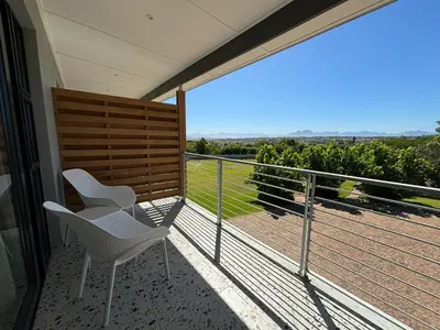 a balcony with two chairs and a view of a field at Swanemeer Apartments in Cape Town