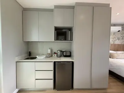 a small kitchen with white cabinets and a microwave at Swanemeer Apartments in Cape Town