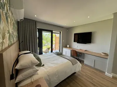 a bedroom with a bed and a desk and a television at Swanemeer Apartments in Cape Town