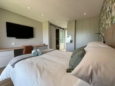 a bedroom with a bed with a tv on the wall at Swanemeer Apartments in Cape Town