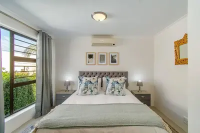 a bedroom with a large bed and a window at Chic, Cozy, Modern, Secure and Centrally Located in Cape Town