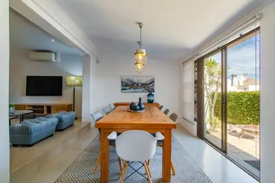 a dining room with a table and a living room at Chic, Cozy, Modern, Secure and Centrally Located in Cape Town