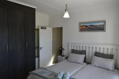 a bedroom with two twin beds and a cabinet at Sundown Apartment in Cape Town