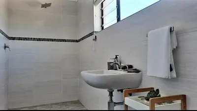 a white bathroom with a sink and a shower at Hermanus reefs in Hermanus