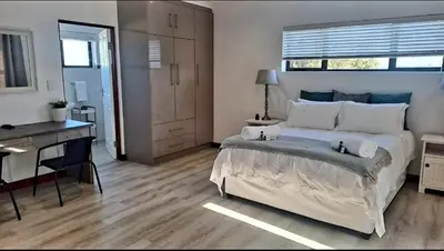 a bedroom with a large bed and a desk at Hermanus reefs in Hermanus