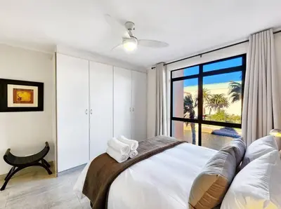 a bedroom with a bed with a view of the ocean at Renovated, Pools, Park, Gym, Parking, Canal walk access in Cape Town