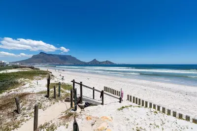 a sandy beach with a bench and the ocean at Neptune Isle 9 in Cape Town