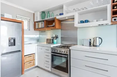 a kitchen with white cabinets and a stove at Neptune Isle 9 in Cape Town