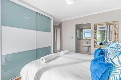 a bedroom with a large white bed with blue pillows at Neptune Isle 9 in Cape Town