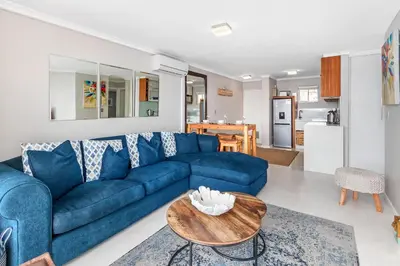 a living room with a blue couch and a table at Neptune Isle 9 in Cape Town