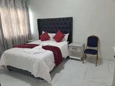 a bedroom with a large bed with a blue chair at Abyssinia Guest House in Cape Town