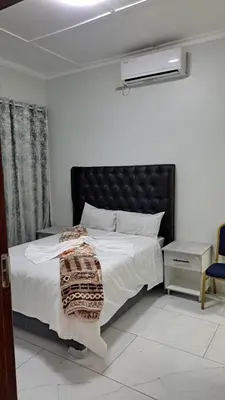 a bedroom with a large bed with a black headboard at Abyssinia Guest House in Cape Town