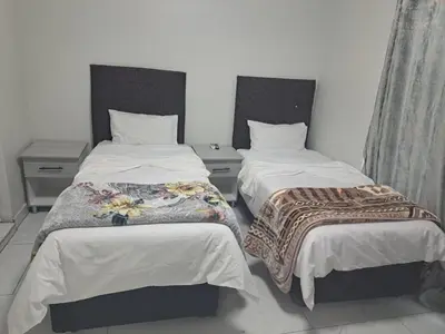 a bedroom with two beds with white sheets at Abyssinia Guest House in Cape Town