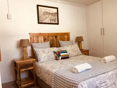 a bedroom with a bed with a wooden headboard at MELJAA GROUP Guesthouse in Cape Town