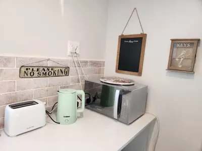 a kitchen counter with a microwave and a toaster at Haus Merwe Self Catering in Cape Town