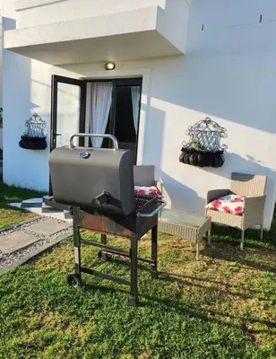 a grill sitting in the grass in front of a house at Haus Merwe Self Catering in Cape Town
