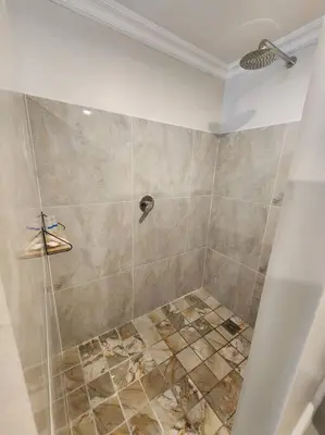 a bathroom with a shower with a tiled shower at Haus Merwe Self Catering in Cape Town