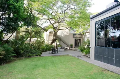 a backyard with a lawn in front of a house at Art and Accommodation Guesthouse in Cape Town