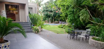 a patio with a table and chairs in a yard at Art and Accommodation Guesthouse in Cape Town