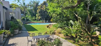 a garden with a table and chairs and a pool at Art and Accommodation Guesthouse in Cape Town