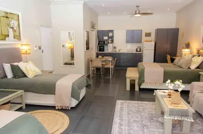 a living room with two beds and a kitchen at Art and Accommodation Guesthouse in Cape Town